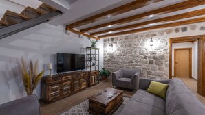 Una sala de estar con un sofá, una mesa de centro, un televisor y una pared de piedra.
