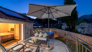 Un patio con sofá, sillas y una mesa, con vistas a una piscina y un muro de piedra.