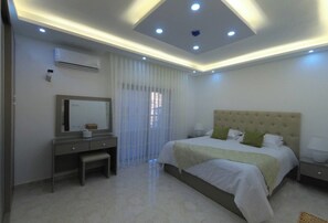 Une chambre moderne avec un grand lit, une table de chevet, un miroir et un appareil de climatisation.