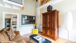 Una sala de estar con un sofá marrón, un aparador de madera, un cuadro y un ventilador de techo.