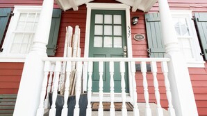 Una casa tradicional con puerta verde, contraventanas blancas y barandilla de porche blanca.