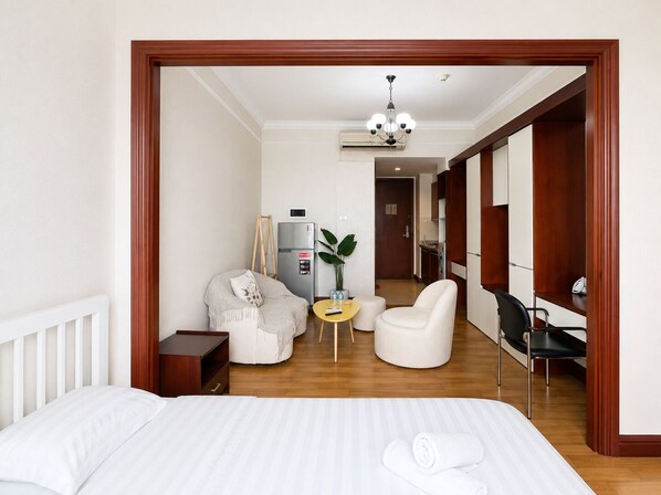 Habitación de hotel con cama, escritorio, silla, una mesita y una planta.