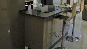 Una cucina moderna con isola centrale, sgabelli da bar e televisore a schermo piatto.