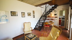 Ein Wohnzimmer mit Treppe, Korbmöbeln und Kunstwerken an den Wänden.