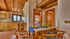 Un coin repas avec une table en bois, des chaises et une vue sur la cuisine.