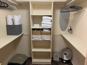 Storage area with shelves, ironing board, and fan.