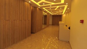 Un pasillo con paneles de madera, iluminación empotrada y un mostrador de recepción blanco.