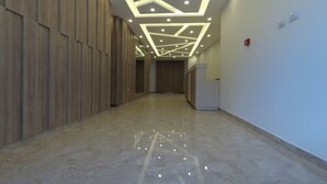 Un pasillo con un diseño moderno en el techo, paneles de madera en las paredes y suelo de mármol.