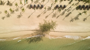 An aerial view of a beach with palm trees, a lone tree, and several spherical structures. - Mövenpick Resort Waverly Phu Quoc (Phu Quoc)