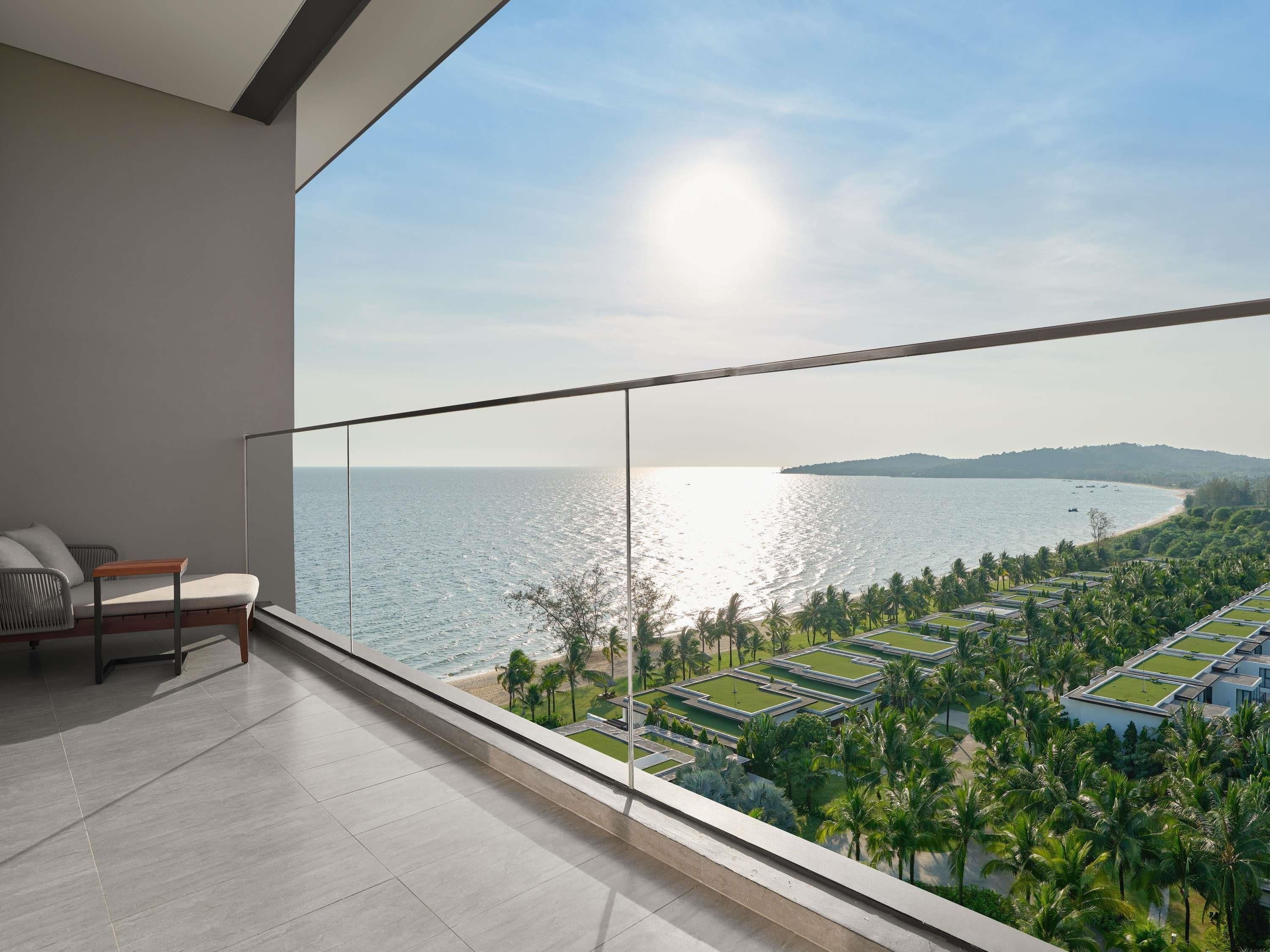 A balcony with a view of the sea and a distant island.