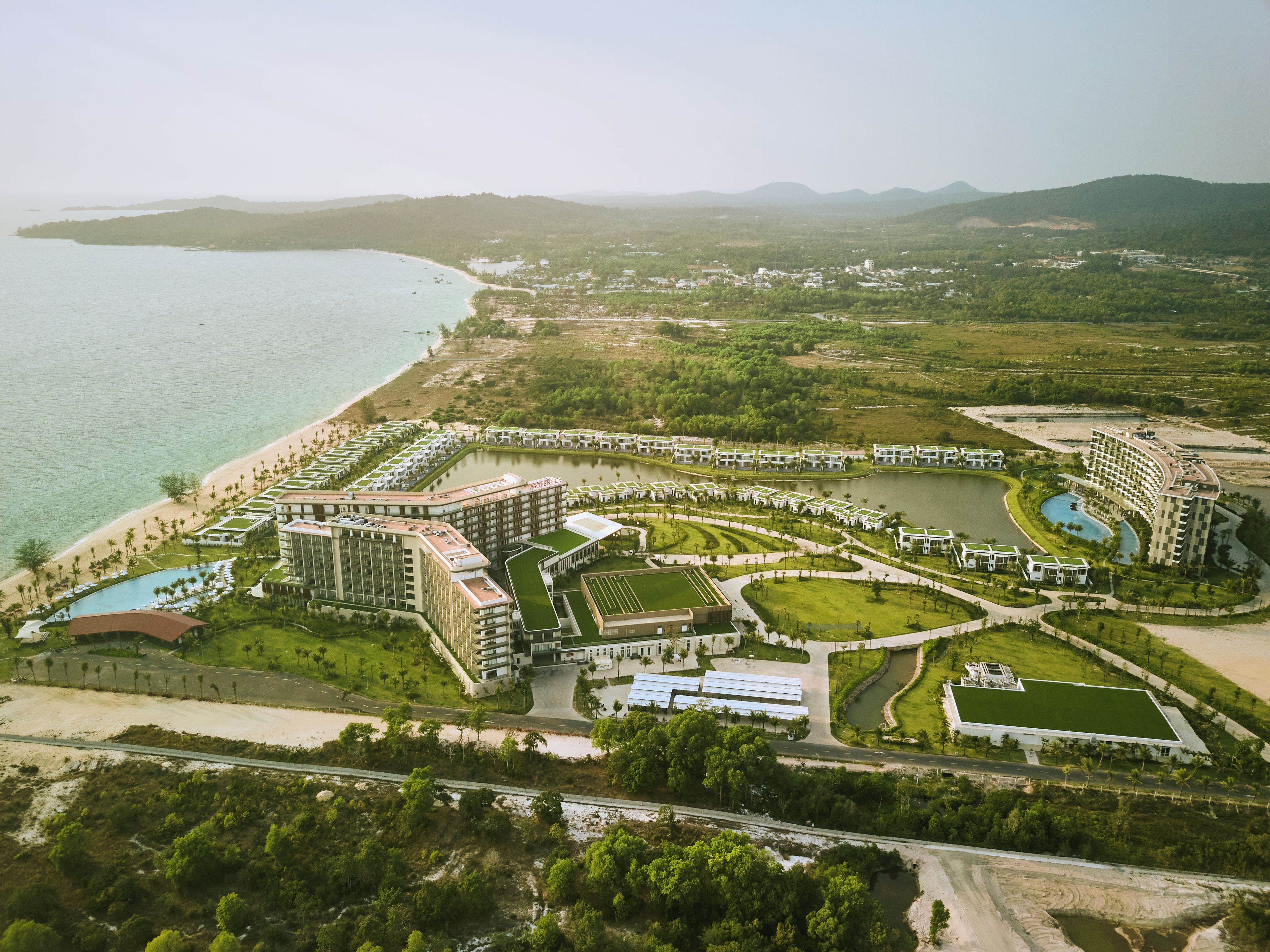 A resort with multiple buildings, a beach, and a large body of water.