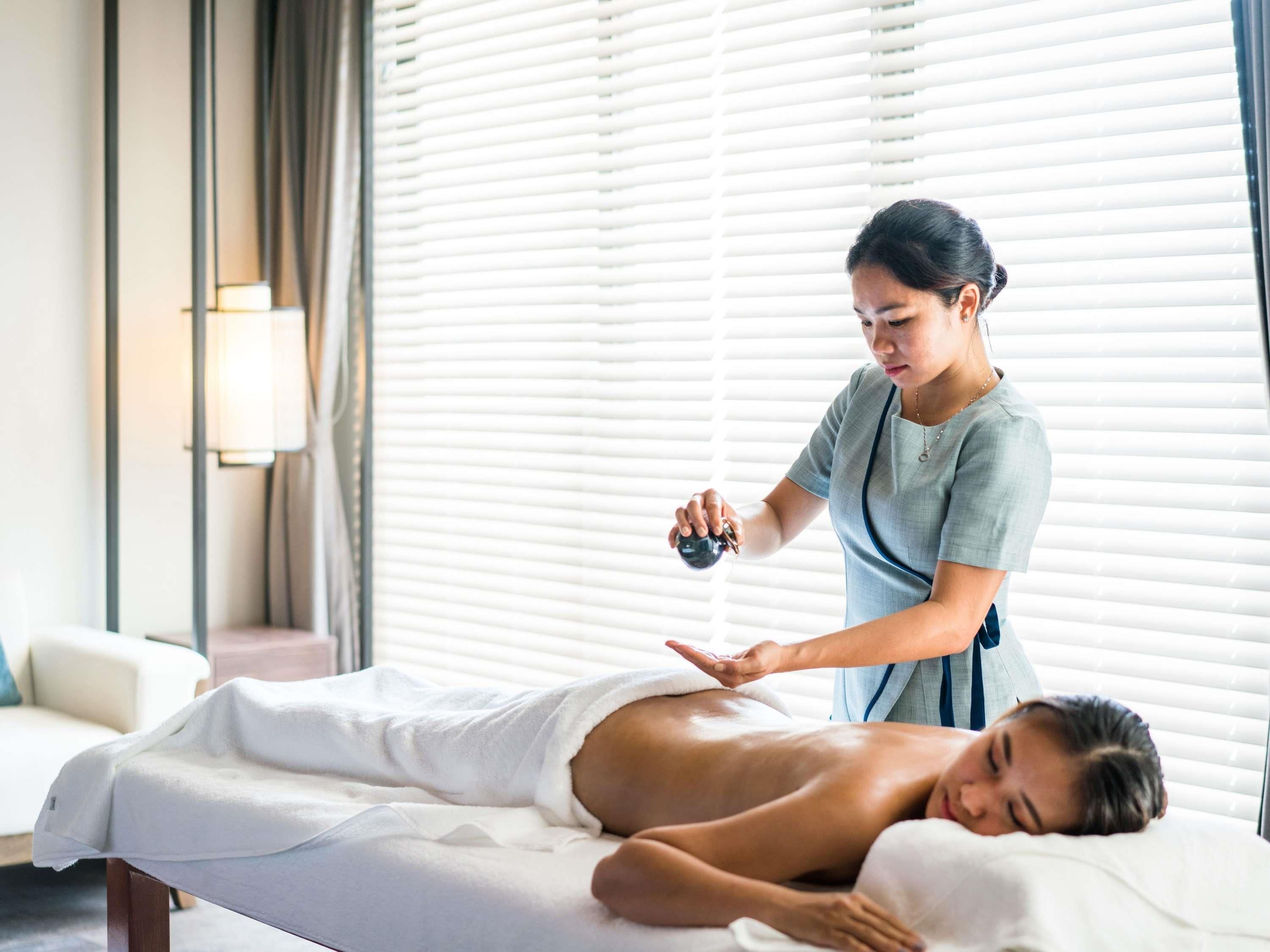 Sesión de masoterapia en una habitación con camilla, terapeuta y cliente.