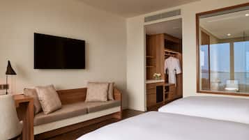 Habitación de hotel con sofá, televisión, escritorio, armario y cama.
