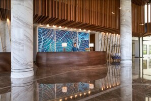 A reception desk with a modern design, marble columns, and a patterned wall.