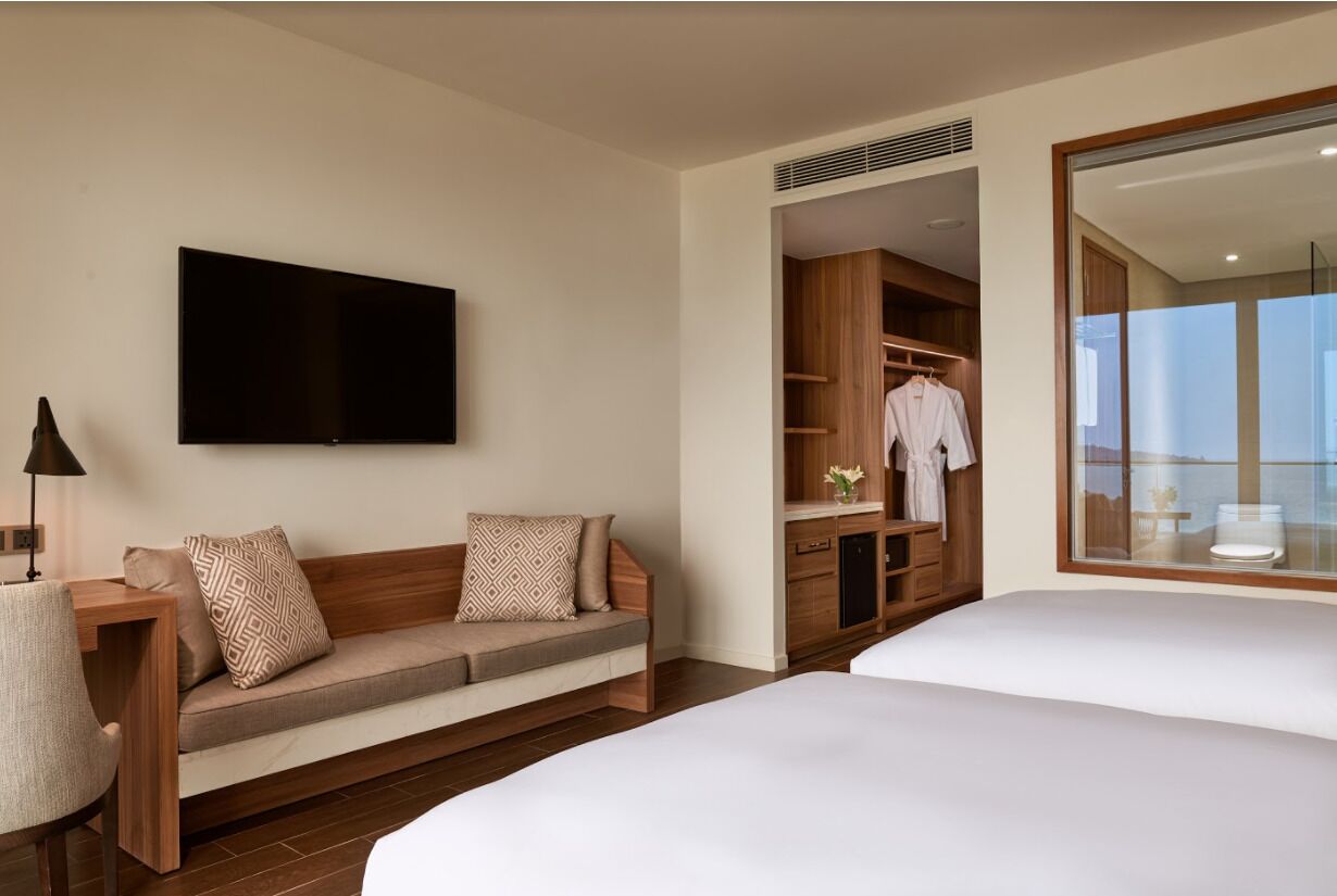 Habitación de hotel con sofá, televisión, armario y cama.