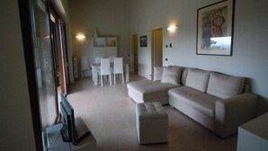 Ein modernes Wohnzimmer mit einer Eckcouch, einem Esstisch mit Stühlen und einem Fernseher.