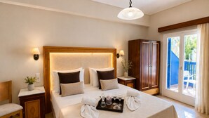 A hotel room with a large bed, bedside tables, a wardrobe, and a view of the outside. - Karidis (Santorini)