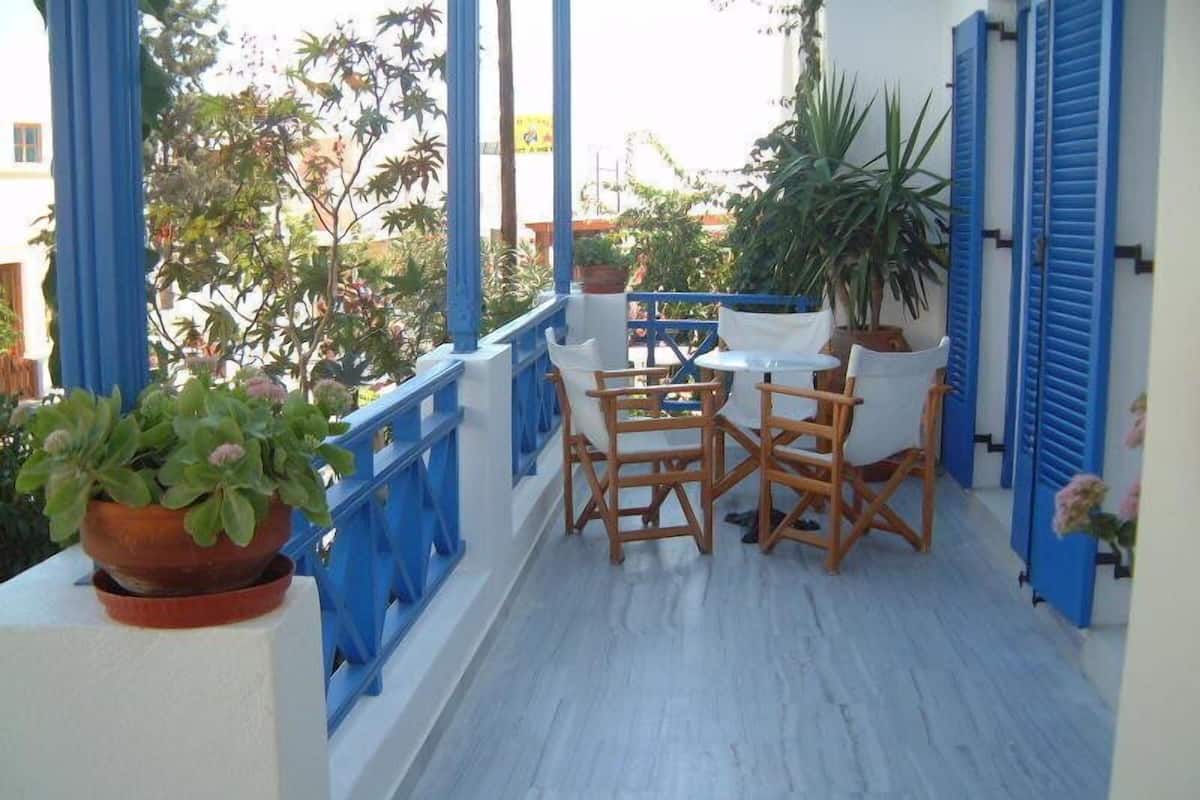 A balcony with blue railings, white walls, and a table with chairs.