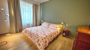 Une chambre à coucher avec un lit, une table de chevet avec une lampe, un lampadaire et une commode.
