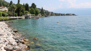 Une vue sur un lac, avec une rive rocheuse, des bateaux et des bâtiments le long du bord de l’eau.
