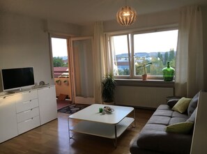 Ein modernes Wohnzimmer mit einer Couch, einem Fernseher und einem Esstisch.