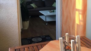 A wooden table with a glass centerpiece and a view into a living room with a sofa, coffee table, and hanging decorations.