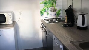 A compact kitchen with a microwave, stove, and coffee maker.