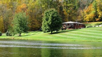 A house with a lawn and a pond in the foreground.
