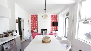 A modern kitchen with a white countertop, a glass-top table, and a hanging light fixture. - Harrington House (Bristol)