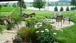 Um espaço de pátio com disposição circular de assentos, cercado por um jardim com diversas plantas e flores.
