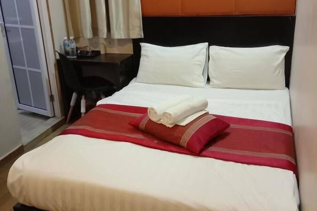 Quarto de hotel com cama, escrivaninha e cadeira.