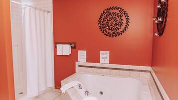 A bathroom with a large bathtub, a shower curtain, a towel rack, and a decorative wall piece.