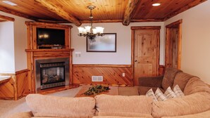 Una sala de estar acogedora con chimenea, televisor y un sofá grande.