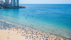 Una spiaggia con molti ombrelloni e persone.