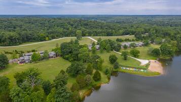 An aerial view of a residential area with houses, a lake, and a forested landscape.