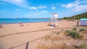 A beach with a lifeguard tower, sandy beach, and clear blue sky. - Sun Beach Apartments (Chania)