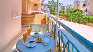 A balcony with a table set for breakfast, including cups, a teapot, and pastries. - Sun Beach Apartments (Chania)