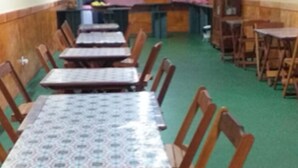 A dining area with multiple tables and chairs, a counter, and a green carpeted floor. - Pousada Ilson (Olímpia)