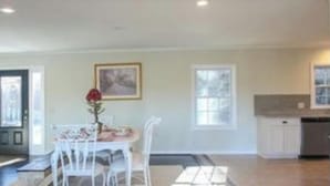 A spacious living area with a dining table and chairs, a kitchen in the background, and a large window providing natural light. - Quiet sunsets on Lanier (Oakwood)