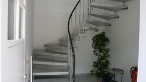 A spiral staircase with metal railings and a potted plant beside it. - Guest house Villa Lina (Bad Herrenalb)