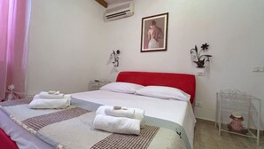 Una camera d'albergo con un letto, due comodini, un quadro appeso alla parete e una finestra con tende.