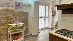Una cucina con un piano cottura a gas, un tavolo con tovaglia floreale e una parete con quadri.