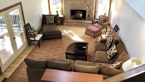 A spacious living room with a fireplace, large windows, and a staircase. - 12 Bedroom XL HotTub 2 HOUSES~44ppl (Lookout Mountain)