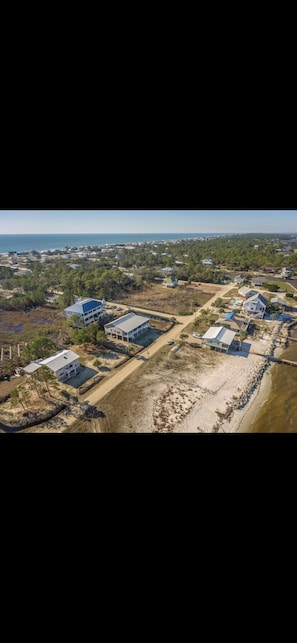 Oversigtsbillede af et kystnære boligområde med flere huse, hvoraf nogle har blå tage, og et sandstrand område.