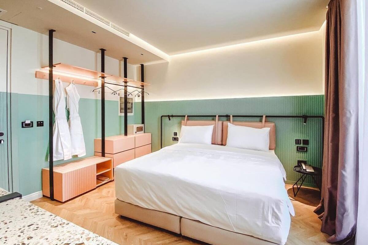Une chambre d’hôtel moderne dotée d’un grand lit, d’un dressing et d’une salle de bain avec douche.