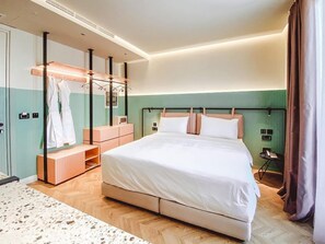 Une chambre d’hôtel moderne dotée d’un grand lit, d’un dressing et d’une salle de bain avec douche.