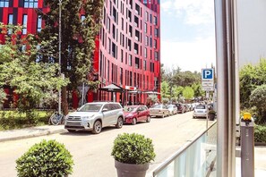 Une vue de rue avec des voitures garées, un restaurant KFC et un bâtiment rouge au design moderne.