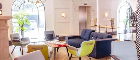Een moderne hotel lobby met een zithoek, een receptiebalie en een marmeren wand.