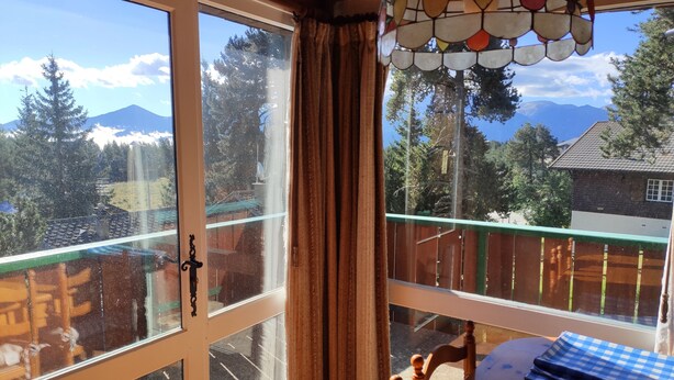 A room with a large window offering a view of a balcony, a wooden table, and a chair. - Chalet 6/7 people at the foot of the Pyrenees 2000 slopes in the forest (Bolquère)