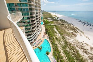 Un hotel moderno con múltiples balcones con vistas a una playa y una piscina.